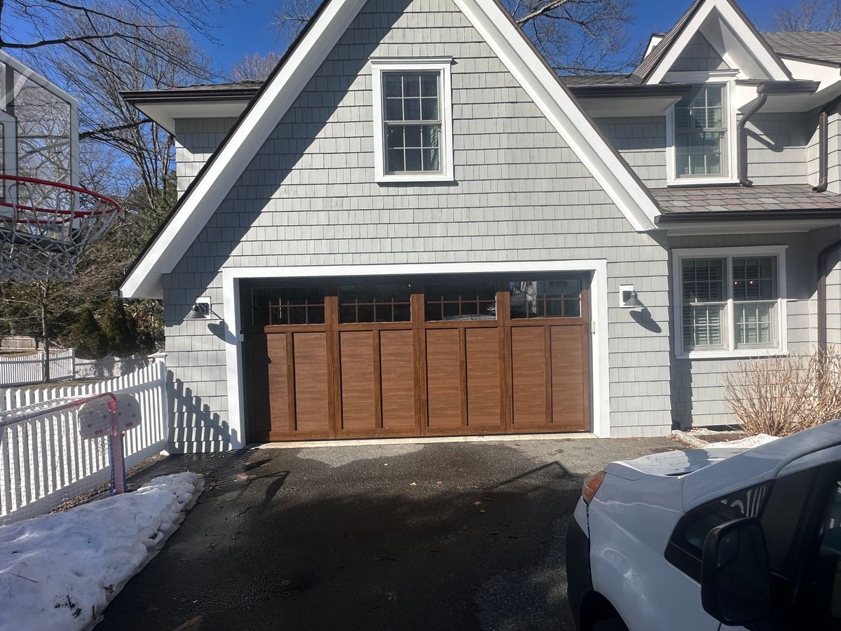 Craftsman-style wood garage door installed on gray shingle home in Massachusetts