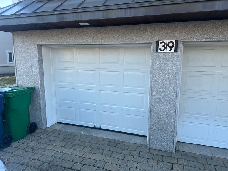 White raised-panel garage door properly aligned after professional repair in MA